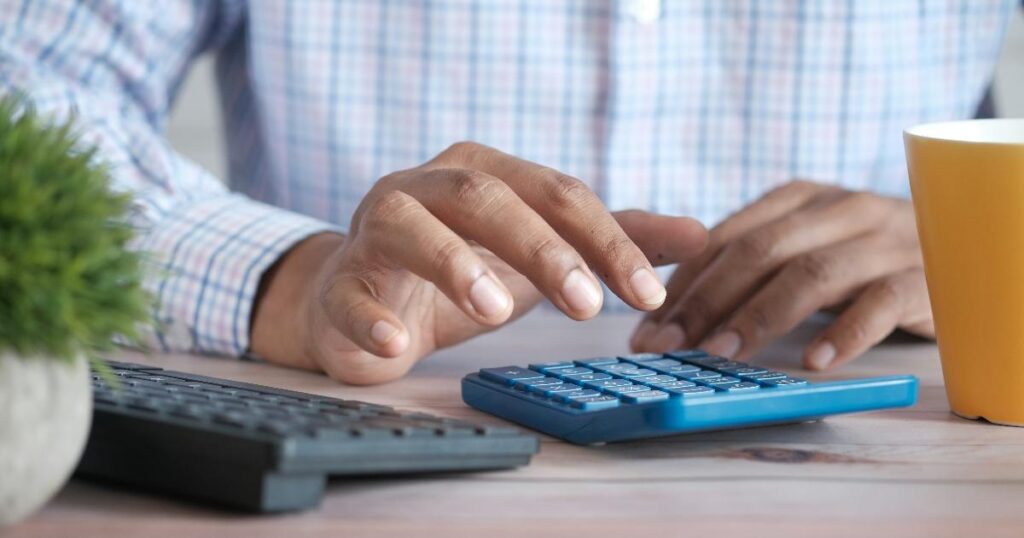 Midyear money audit notes beside a budget spreadsheet and calculator, showing a financial plan tested against current realities