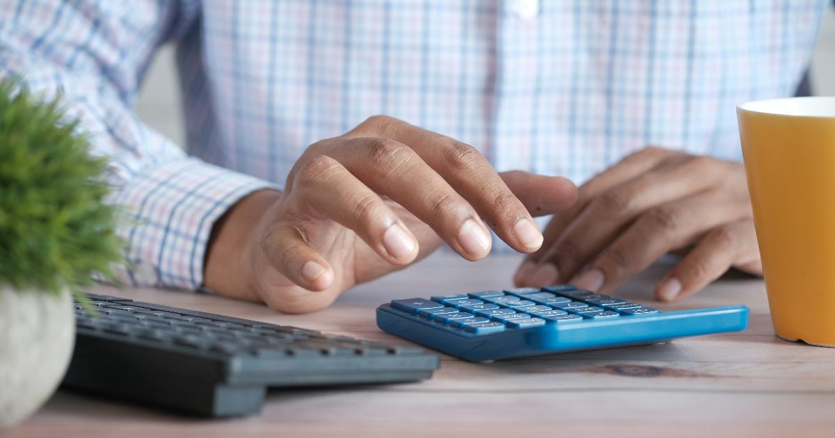 Midyear money audit notes beside a budget spreadsheet and calculator, showing a financial plan tested against current realities