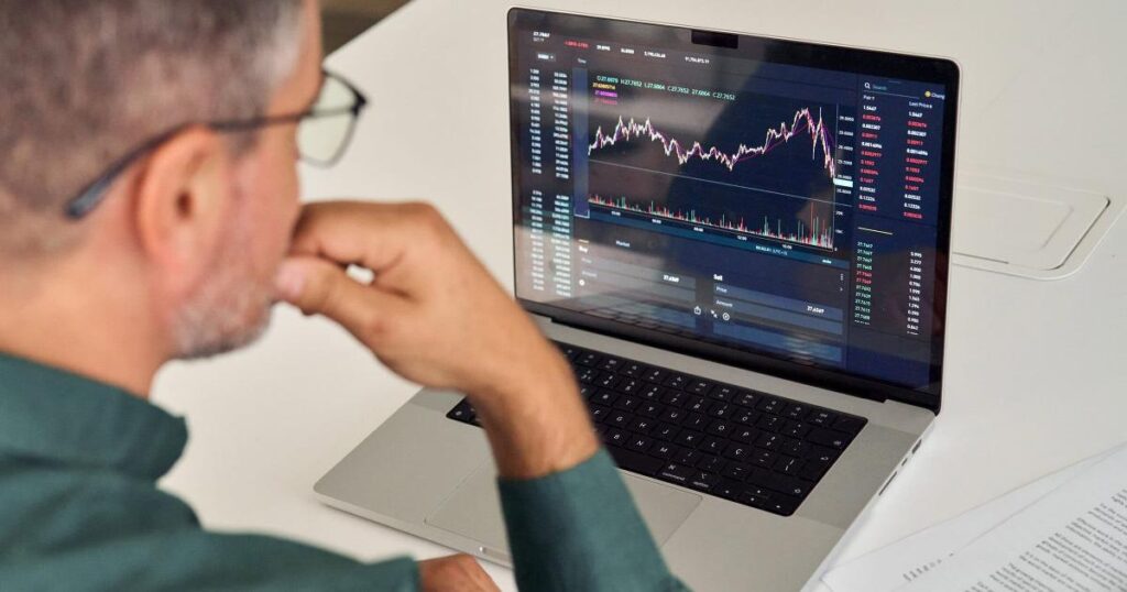 Analyst reviewing market data screens while AI-generated signals converge in a crowded trading environment, showing the risk of AI validation mistakes