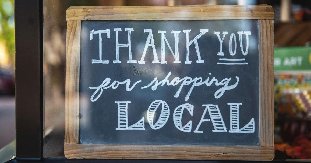 A small storefront sign and map pin illustrating a local demand experiment for a new business